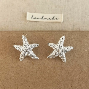 Gros plan sur les boucles d'oreilles étoile de mer en argent et zircons sur fond rustique