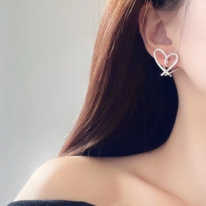 Minimalist heart-shaped stud earrings with sparkling cubic zirconia on female model