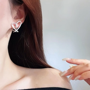 Elegant silver heart earrings with pavé cubic zirconia worn by a model