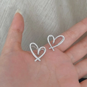 Detail of silver heart earrings with micro-paved cubic zirconia in ribbon design
