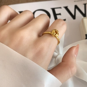 Minimalist gold knot ring for women featuring a polished twisted design on silk background