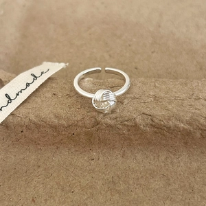 Close-up of silver knot ring with multi-layer wire design and adjustable open band
