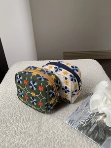 Detailed embroidery texture on mini cotton makeup bags with floral patterns and zippers