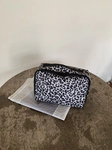 Detail van de make-uptas met luipaardprint, stevig handvat en dubbele ritssluiting