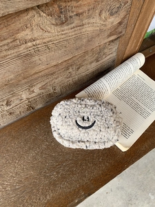 Detail eines beigen Plüsch-Geldbeutels mit Smiley auf einer Holzoberfläche
