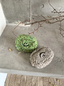 Detailstruktur der grünen und beigen Plüsch-Minitaschen mit aufgesticktem Smile-Gesicht