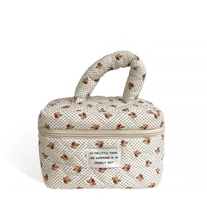 Quilted floral makeup bag in beige with red flowers and a top handle for storage