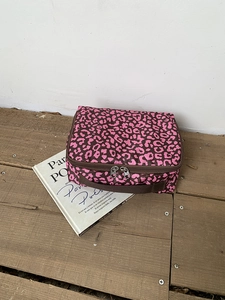 Detail van de roze toilettas met luipaardprint met ritssluiting en stoffen handvat