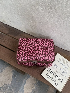 Detail van de roze toilettas met luipaardprint, ritssluiting en bruin handvat