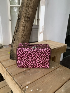Roze toilettas met luipaardprint op houten bank met dubbele ritsen en handvat aan top