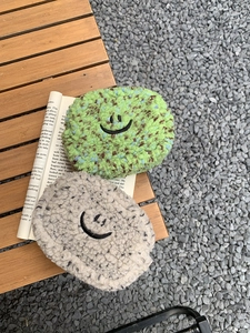Detailansicht der Plüsch-Smiley-Geldbörsen in Grün und Grau auf Vintage-Büchern