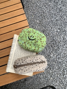 Nahaufnahme von Plüsch-Mini-Kosmetiktaschen mit Smiley-Stickerei auf einem Holztisch