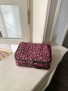 Gedetailleerd zicht op de roze make-uptas met luipaardprint, dubbele rits en zijhandvat