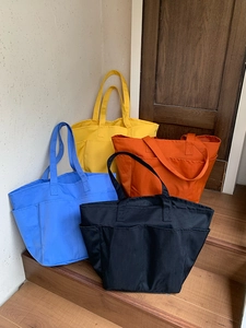 Grandi borse tote in nylon in quattro colori disposte su gradini per l'uso quotidiano