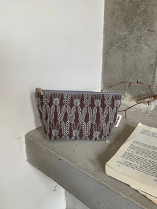 Detail of embroidered rabbit pattern on cotton linen makeup bag with a gold zipper
