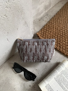Brown linen makeup bag with rabbit embroidery, styled with sunglasses and book