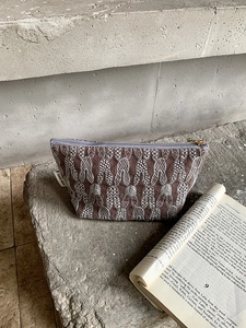 Close-up of brown embroidered rabbit cosmetic bag with golden zipper and woven label