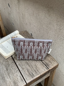 Detailed close-up of rabbit embroidery pattern and golden ball zipper on canvas makeup bag