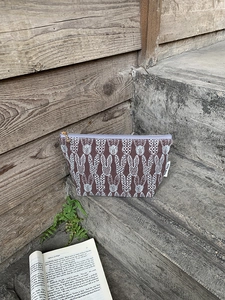 Close-up of brown embroidered rabbit cosmetic bag with purple zipper and golden puller