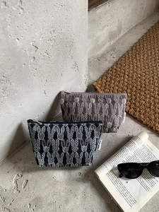 Detailed close-up of embroidered rabbit cosmetic bags with gold zippers and linen texture