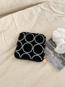 Détail de la trousse de maquillage brodée noire avec motif marguerite et zip doré