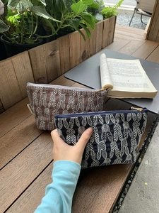 Detail of embroidered rabbit pattern on cotton linen makeup bag with golden zipper