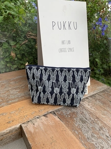 Navy blue canvas makeup bag with white rabbit embroidery on a wooden bench outdoors