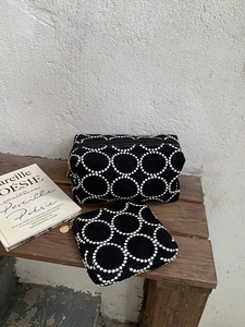 Détail du motif cercles entrelacés brodés sur les pochettes en tissu noir et doré