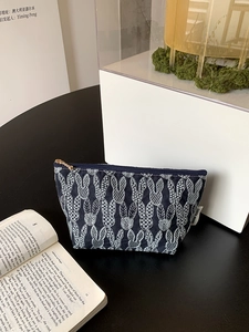 Detail of navy cotton storage bag featuring white rabbit embroidery and gold metal zipper
