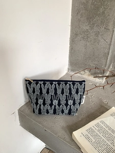 Close-up of cotton linen pouch with embroidered rabbit patterns and gold zipper detail