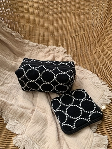 Détail du set de deux trousses de maquillage noires avec broderie et zips dorés