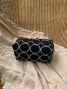 Détail de la trousse de maquillage noire brodée avec motifs anneaux et fermeture dorée