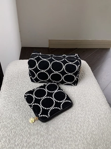 Détail d'un ensemble de trousses à maquillage brodées noires sur un support en peluche