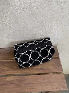 Détail de broderie florale sur trousse à cosmétiques en toile noire sur un banc