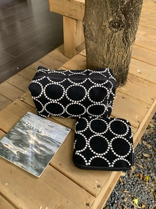 Détail d'un ensemble de trousses de maquillage brodées noires avec motifs cercles blancs