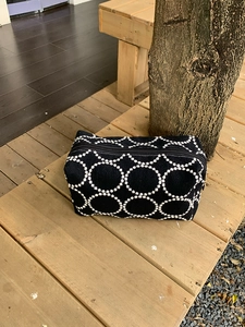 Détail de broderie sur grand sac à cosmétiques en toile noire avec fermeture dorée