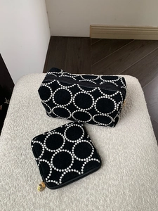 Détail de pochettes en tissu noir avec broderie blanche et fermetures éclair dorées