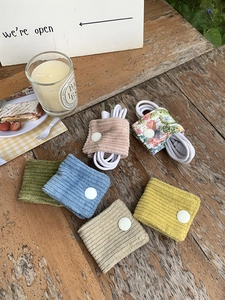 Close-up of corduroy cable organizers in various colors on a rustic wooden desk