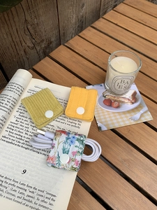 Detailed fabric cable organizers in corduroy and floral patterns on a vintage book