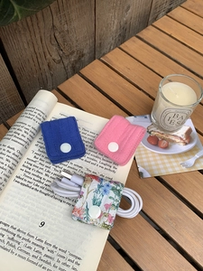 Detail of fabric cable organizer with snap button on a wooden desk with floral pattern