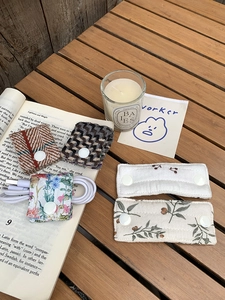 Close-up of fabric cable organizers with floral and tweed patterns on a wooden desk