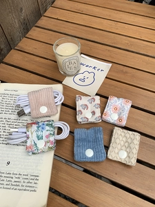 Flat lay of colorful fabric cable organizers with snap buttons on a wooden desk