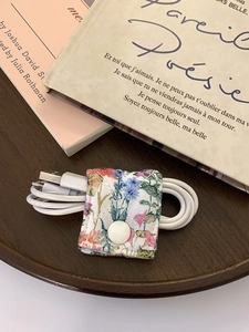 Floral fabric cable organizer with white snap button on a walnut wood tray
