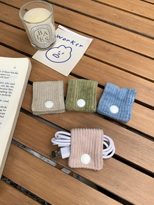 Detail of corduroy cable organizers in four colors on a rustic wooden table setup