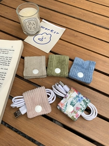 Detailed shot of cord organizers in corduroy and floral fabric on a wooden desk