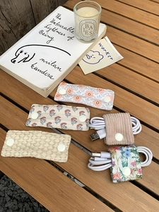 Detail showing assorted fabric cable organizers in floral and corduroy textures on wood
