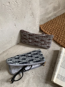 Detail of embroidered linen glasses pouch with gold zipper and leaf patterns