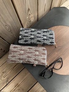 Detailed view of linen eyewear pouches with leaf embroidery and metal zipper pulls