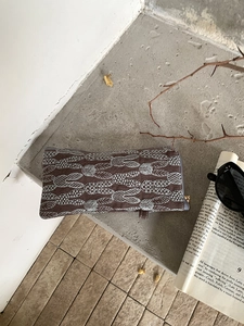 Close-up of linen embroidery eyewear pouch with leaf pattern on a rustic background