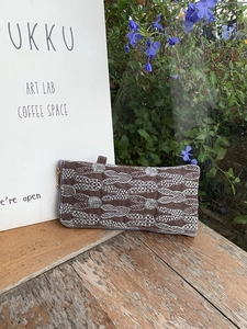 Detail of embroidered rabbit pattern on brown linen pouch with gold zipper and wood background